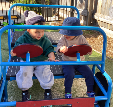 Toddlers playing together in a toy car at Romsey Early Learning